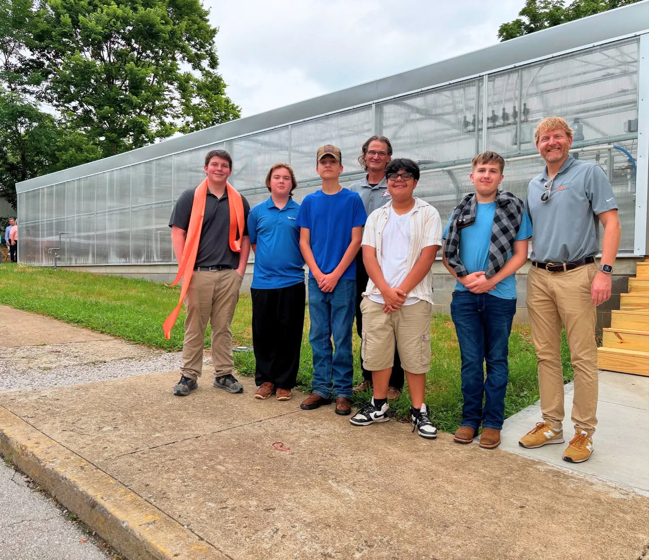 Stephen standing with a student group outside a school greenhouse